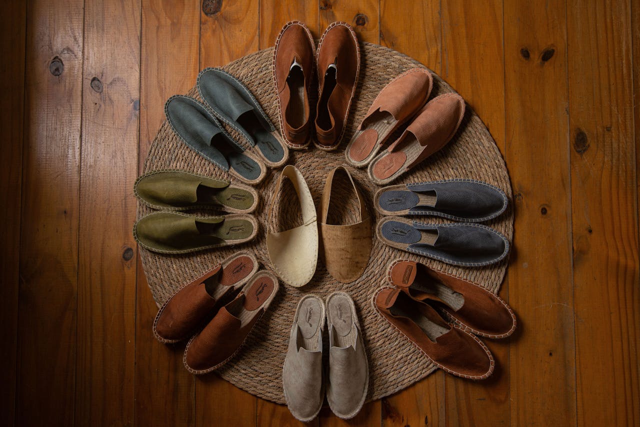 Top view of assorted colorful espadrilles arranged in a circle on a wooden floor.